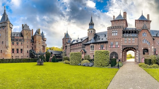A large, historic brick castle with multiple towers and a well-maintained garden.
