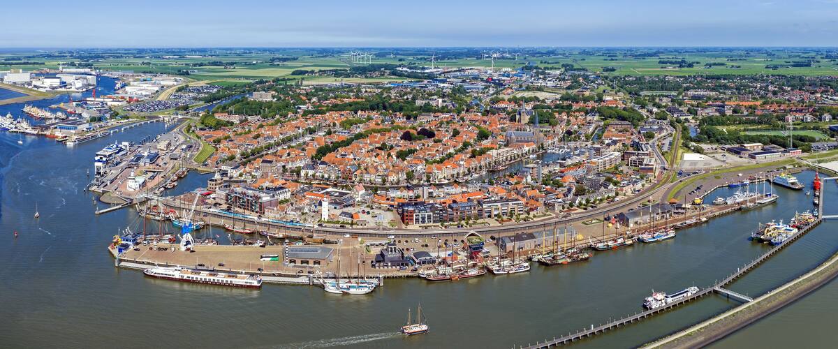 Aerial view of the historic port city of Harlingen with traditional Dutch architecture, orange-tiled rooftops, and a bustling harbor filled with ships in Harlingen, Friesland, Netherlands.
