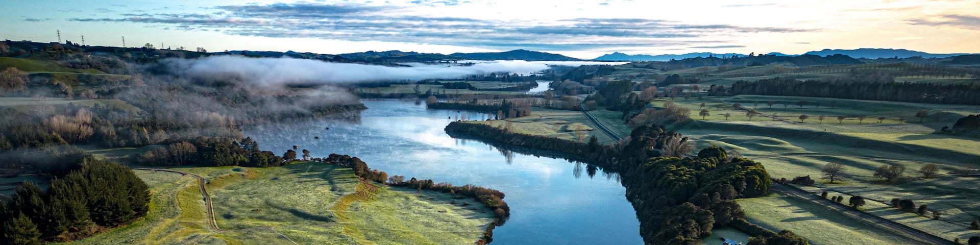 A river meandering through a valley with fields and forests.