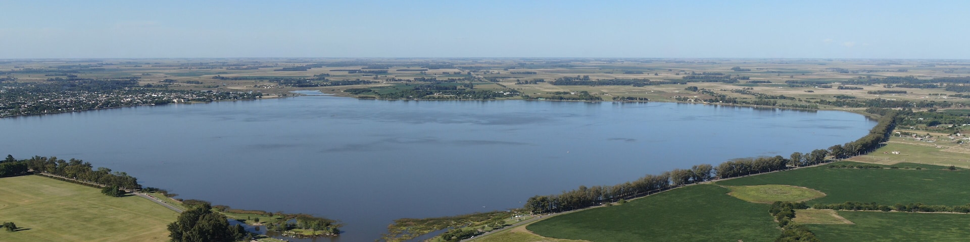 Um lago grande rodeado por campos verdes e uma pequena cidade.