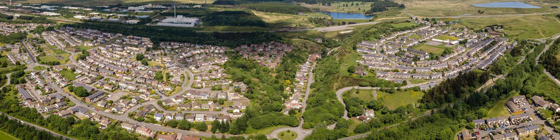 A residential area with winding roads, green fields, and scattered houses.