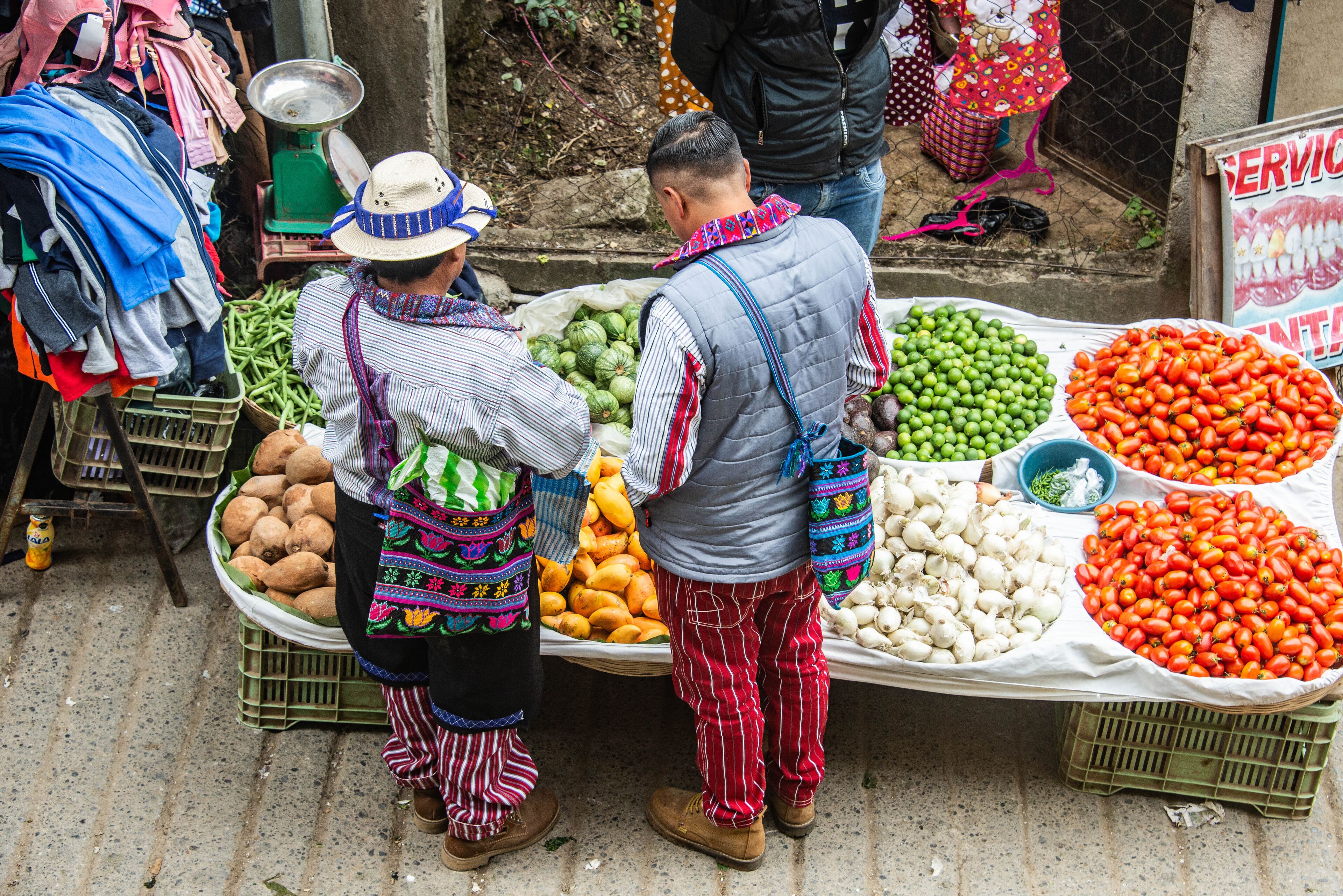 A street market with vendors selling vegetables and fruits.
