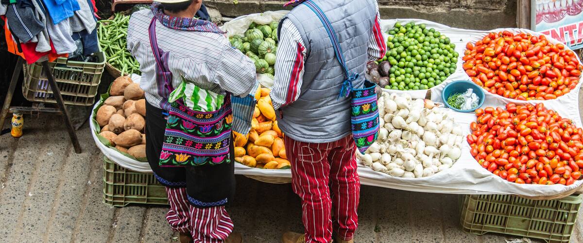 A street market with vendors selling vegetables and fruits.