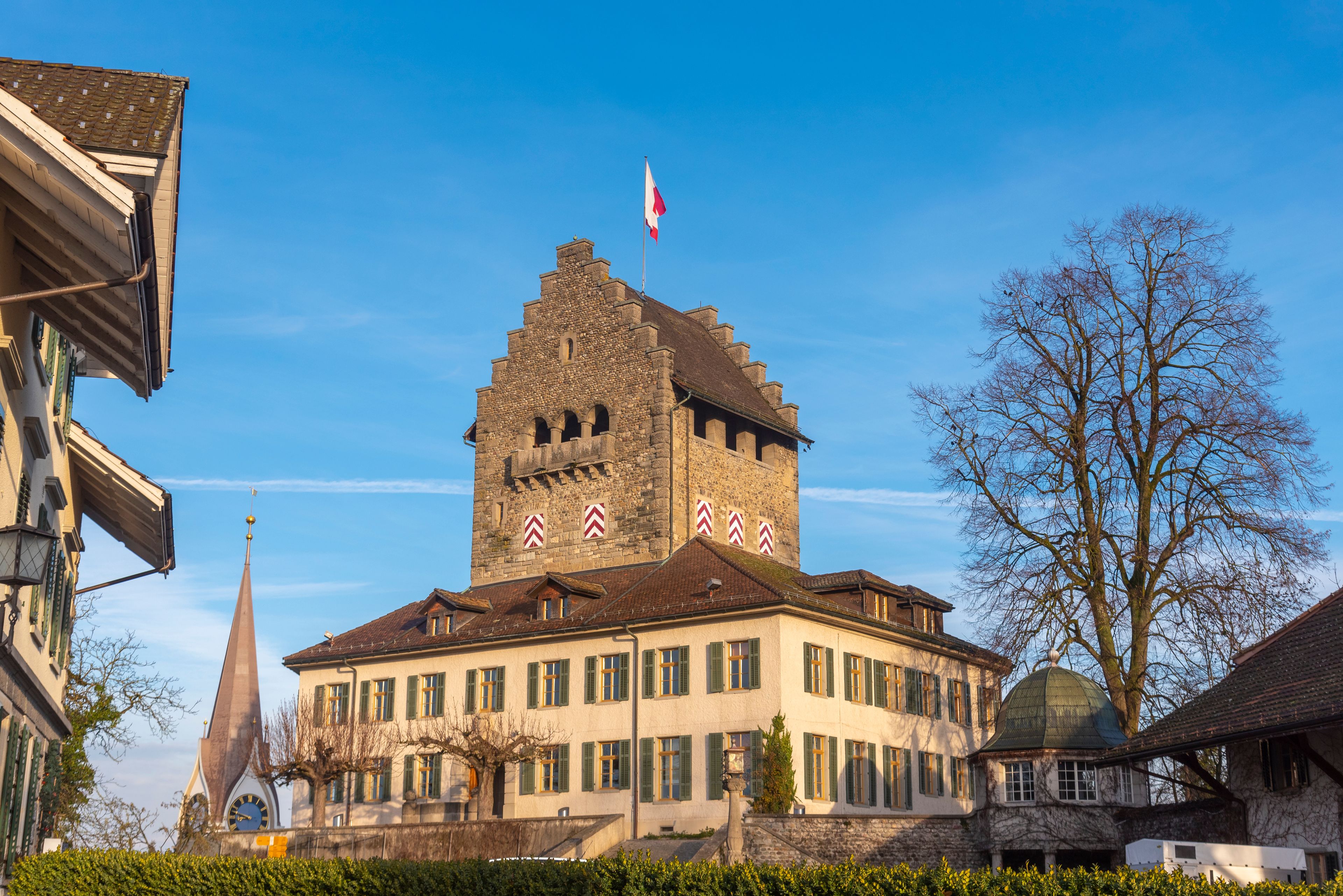 A historic building with a tower, a clock tower, and a flag.