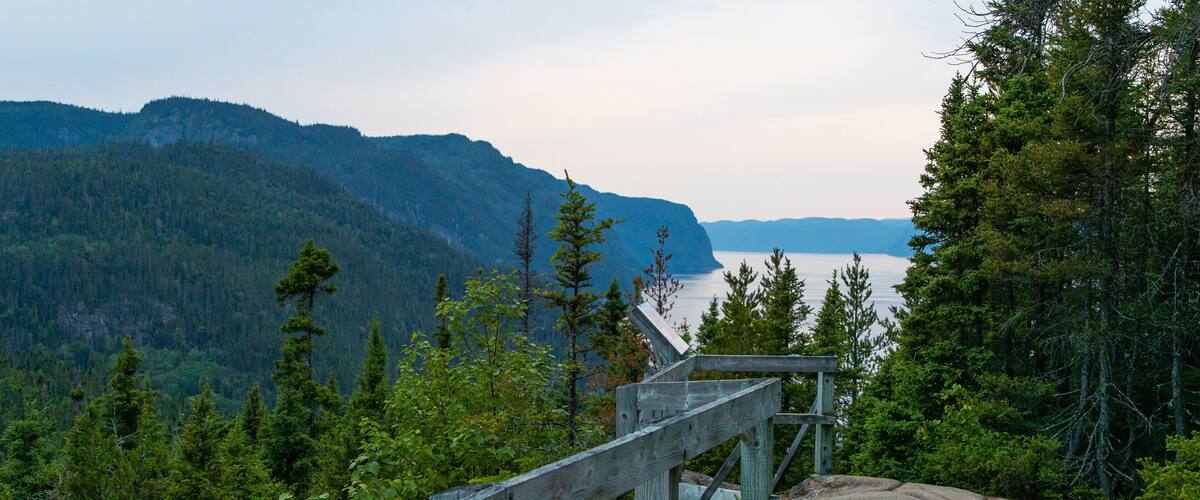 A wooden lookout platform overlooking a lake with mountains in the background.