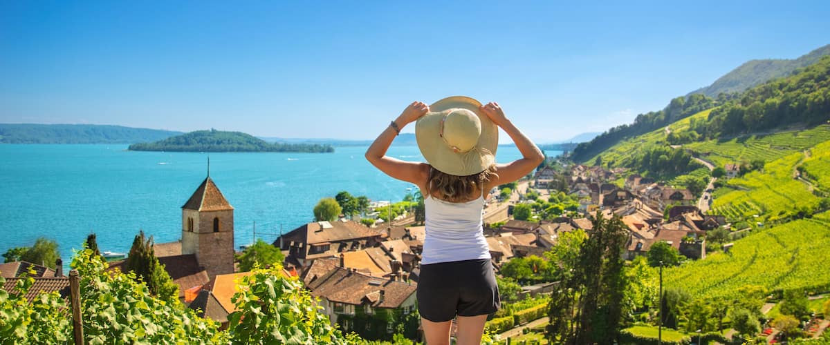 A woman overlooking a coastal town with vineyards and a church.