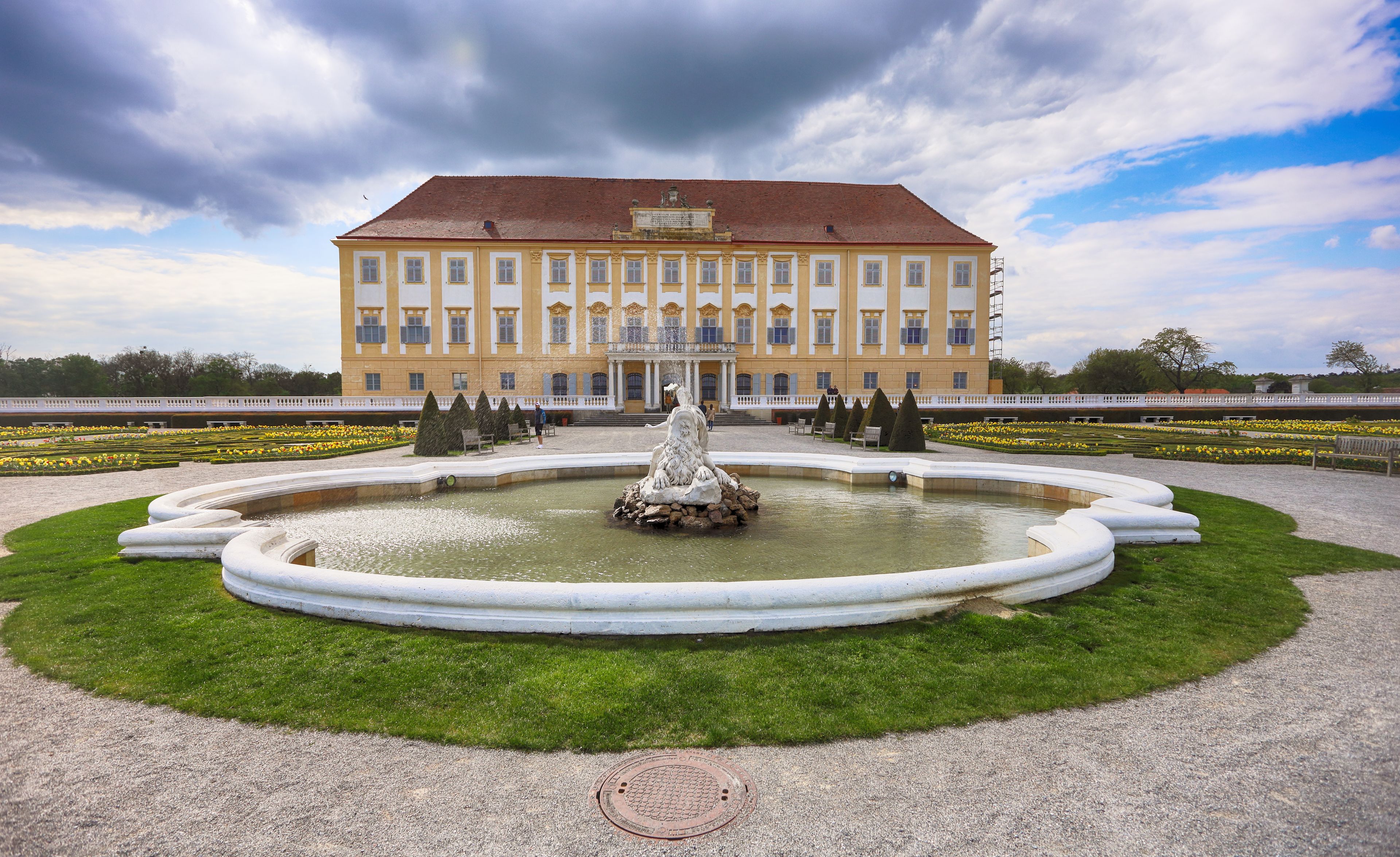 Ein großes, gelbes Gebäude mit einem Brunnen davor.