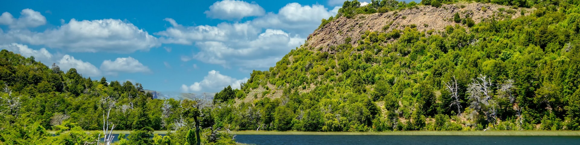 Landscape of lake Rosales surrounded by a forest and a few hills in San Martin de los Andes, Neuquen, Argentina. Taken on a warm summer morning