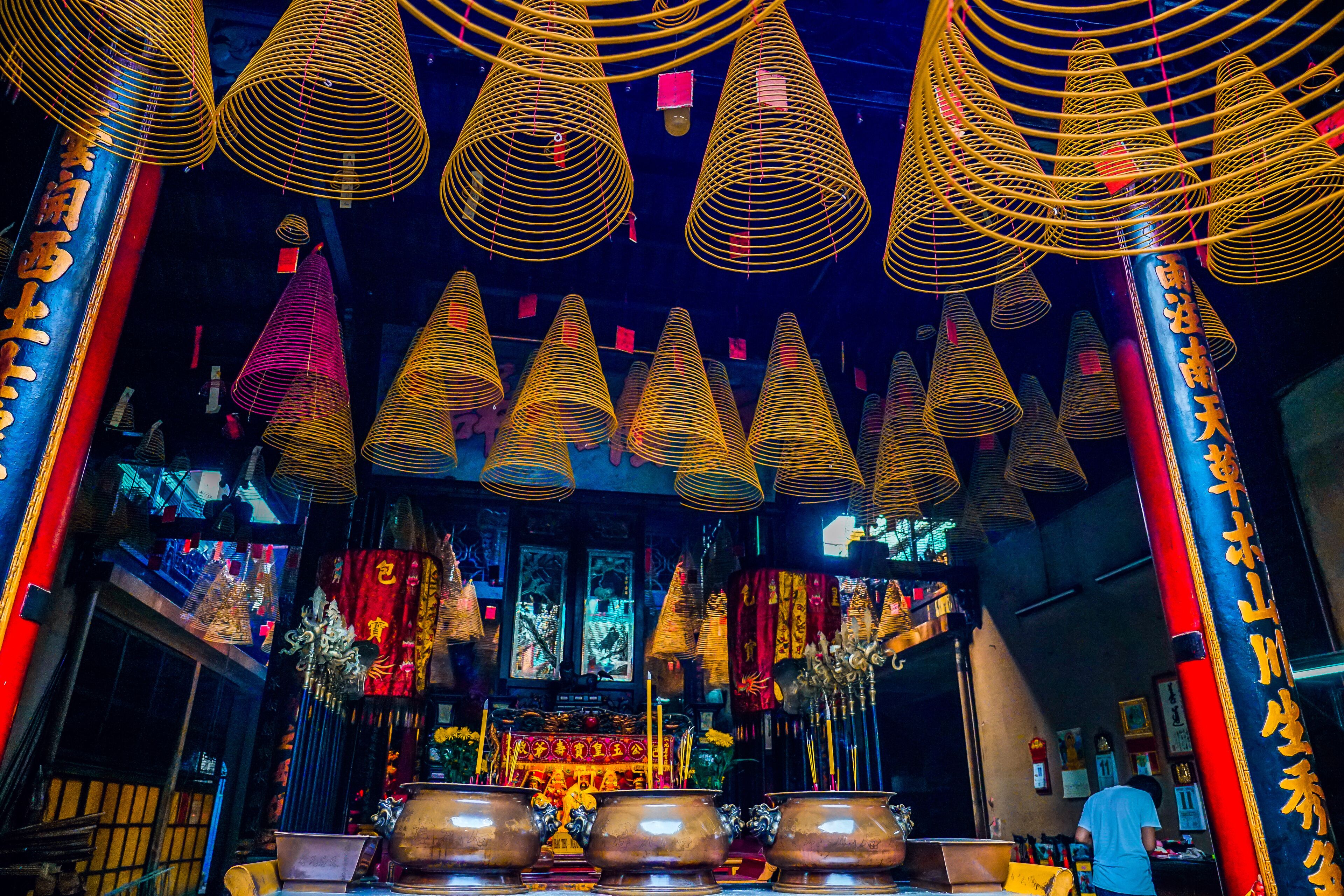 A temple interior with multiple golden conical structures, red and gold decorations, and traditional Chinese incense burners.