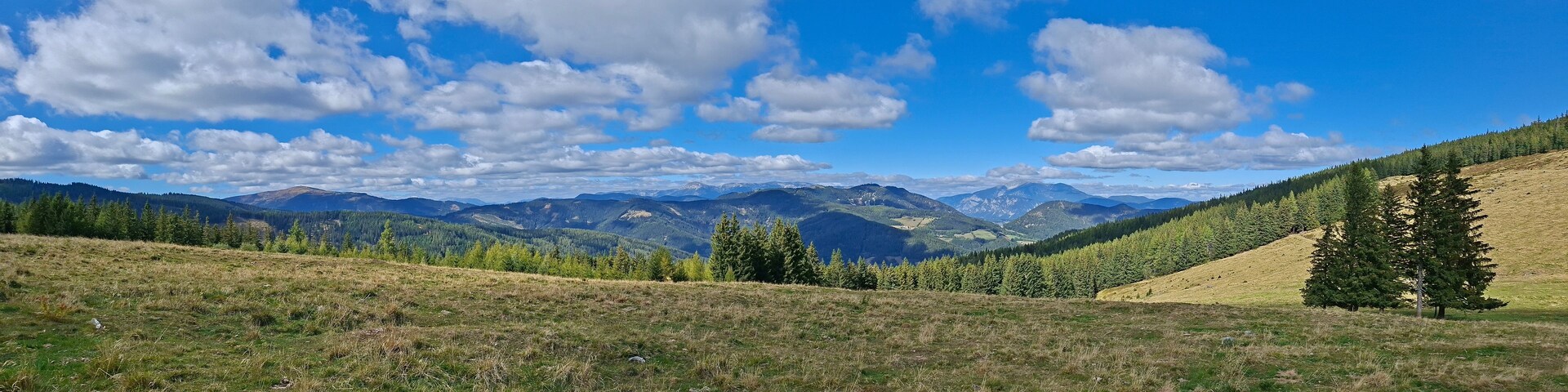 Un paysage montagneux, avec un ciel dégagé et quelques nuages épars.