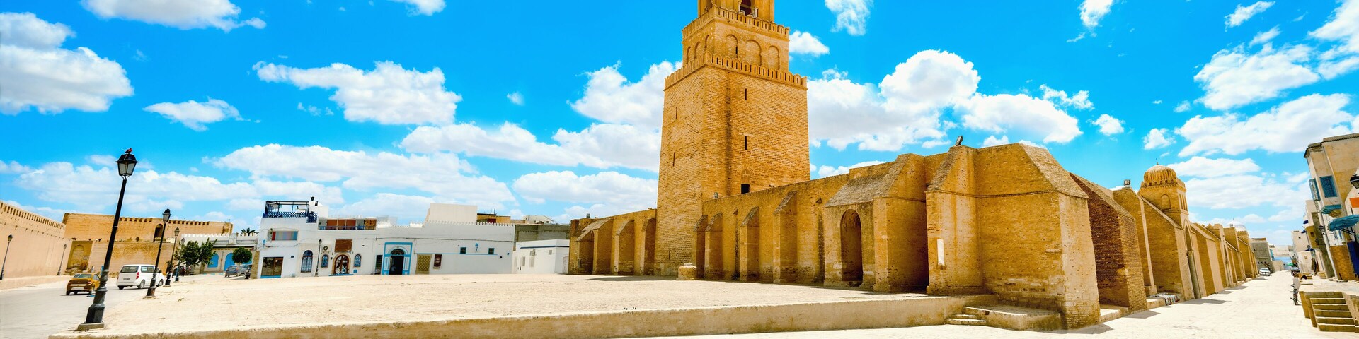Una plaza histórica con una torre destacada y una mezquita.
