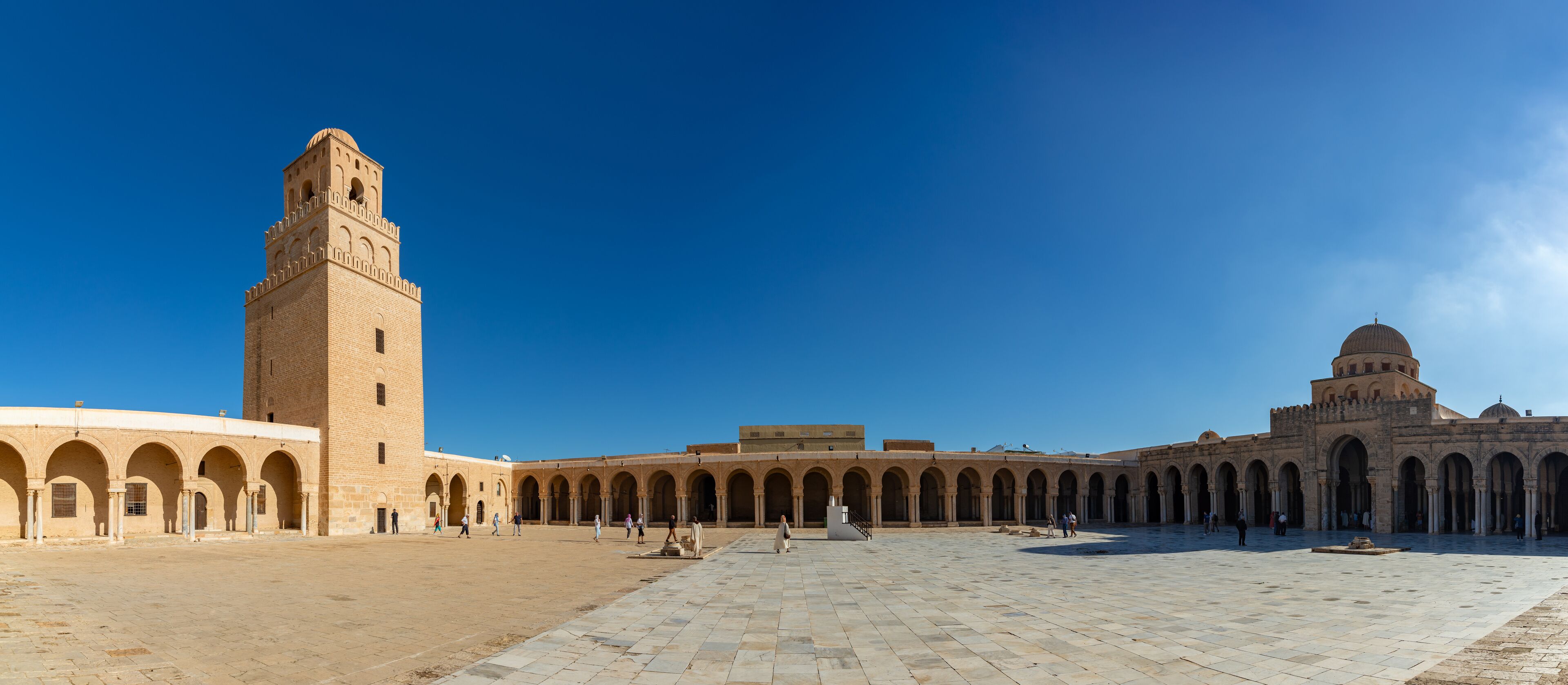A historic courtyard with a tall tower and a dome.