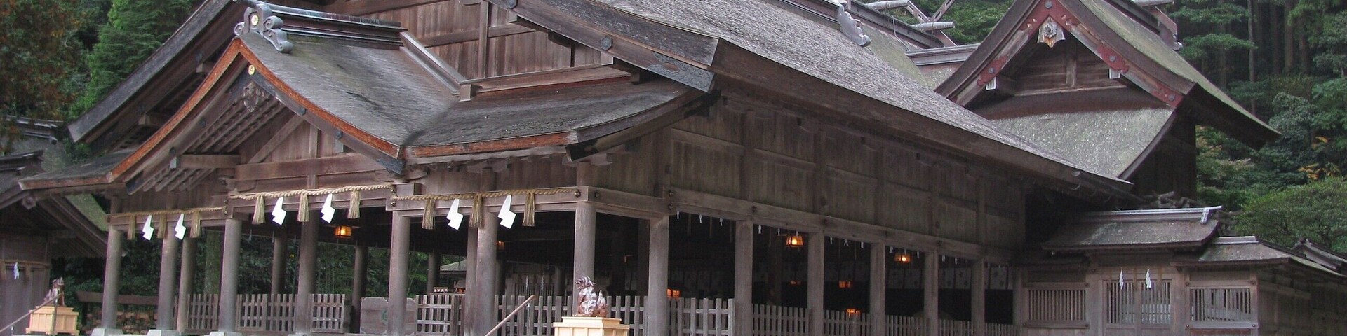 Un templo tradicional de madera con techo inclinado, columnas de madera y una escalera de piedra que conduce a la entrada.