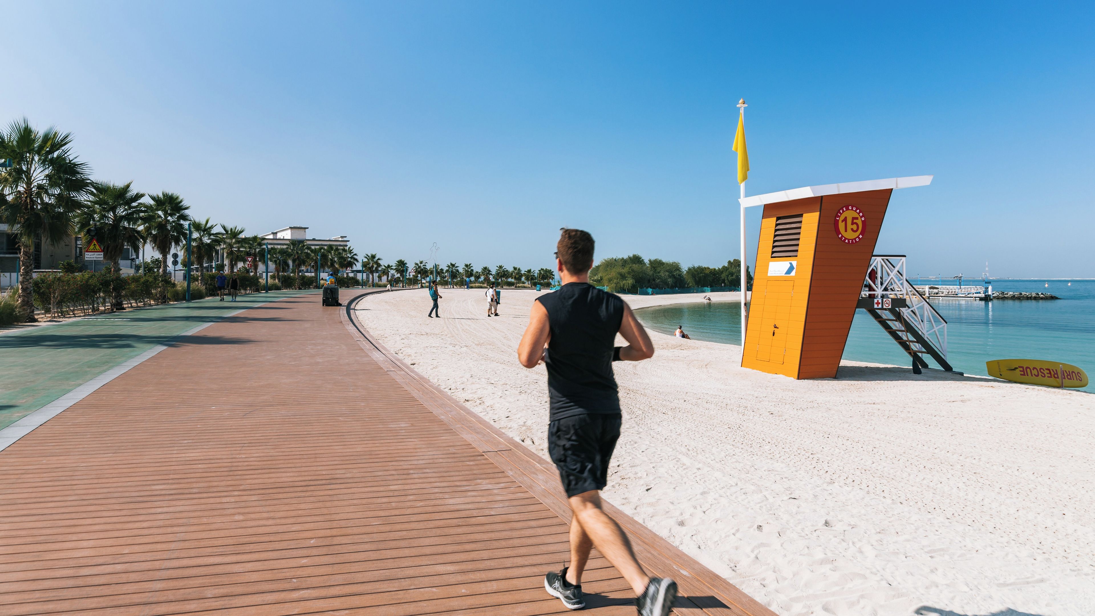 A wooden boardwalk leading to a beach with a lifeguard tower and a lifeguard stand.