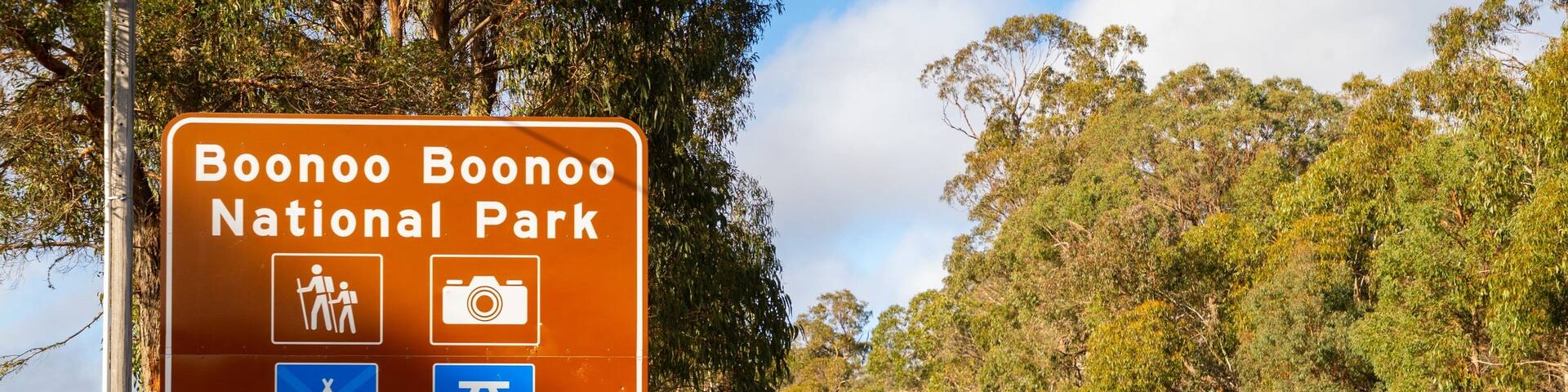 Señal para el Parque Nacional Boonoo Boonoo con símbolos para senderismo, fotografía, camping y una tienda de campaña. Indica girar a la izquierda en 500 metros.