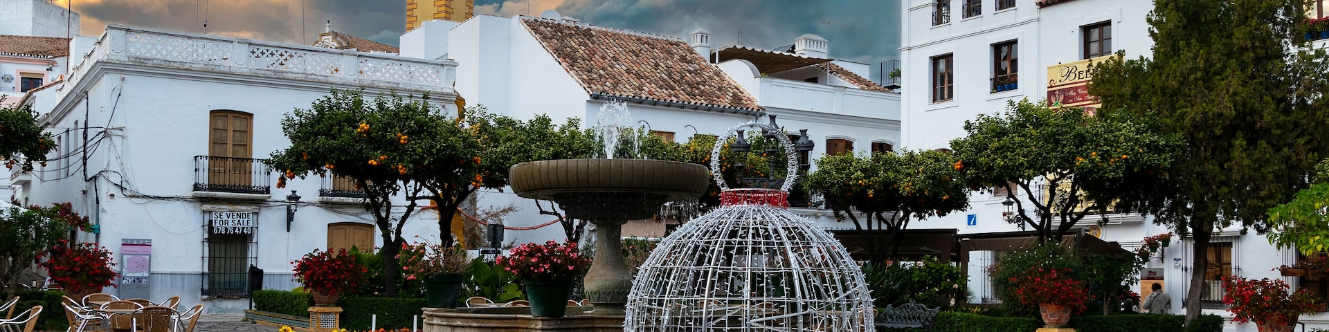 A plaza with outdoor seating, a fountain, and historic buildings.