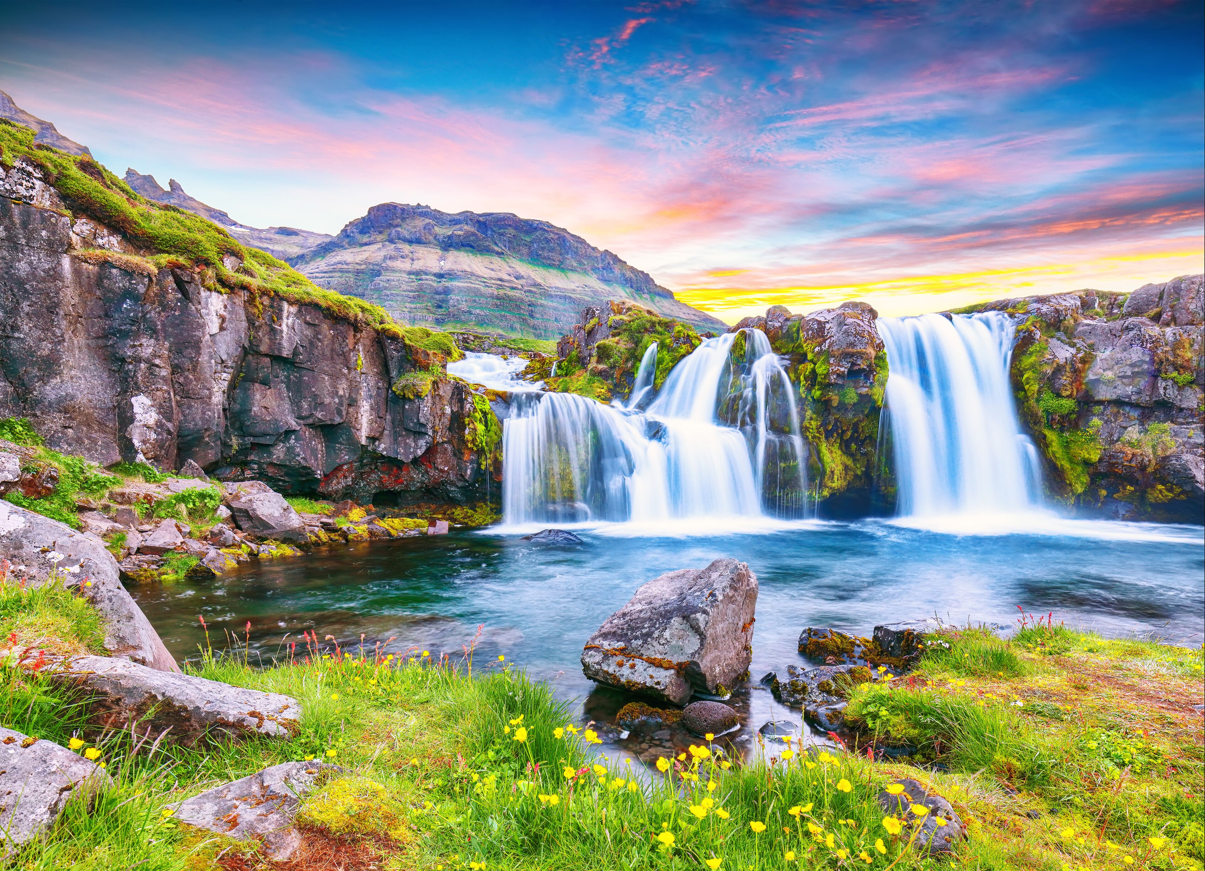 Dramatic view on Kirkjufellsfoss waterfall  near Kirkjufell mountain at sunset