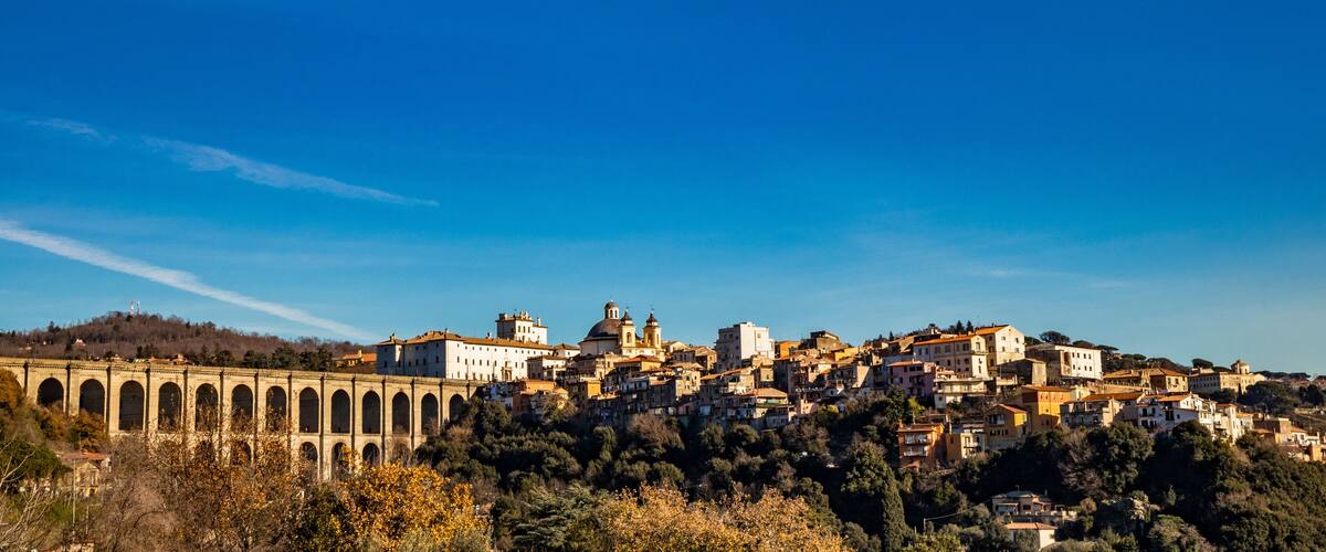 A coastal town with a prominent bridge, historic buildings, and a hilltop church.