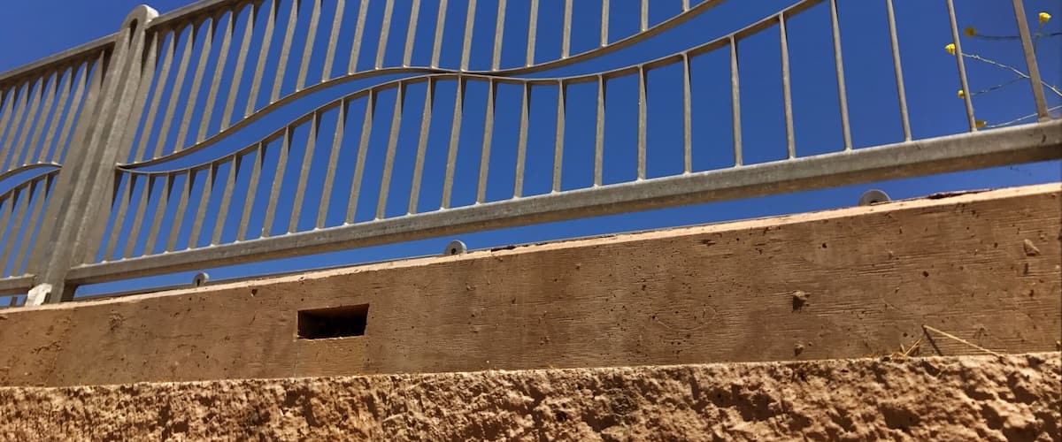 A metal fence with vertical bars and a curved top rail.
