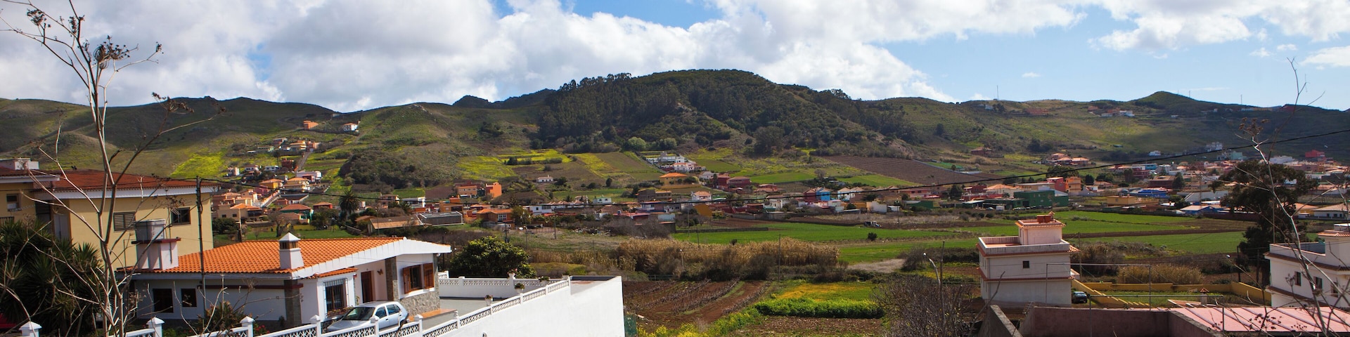 A rural landscape with rolling hills, scattered houses, and agricultural fields.
