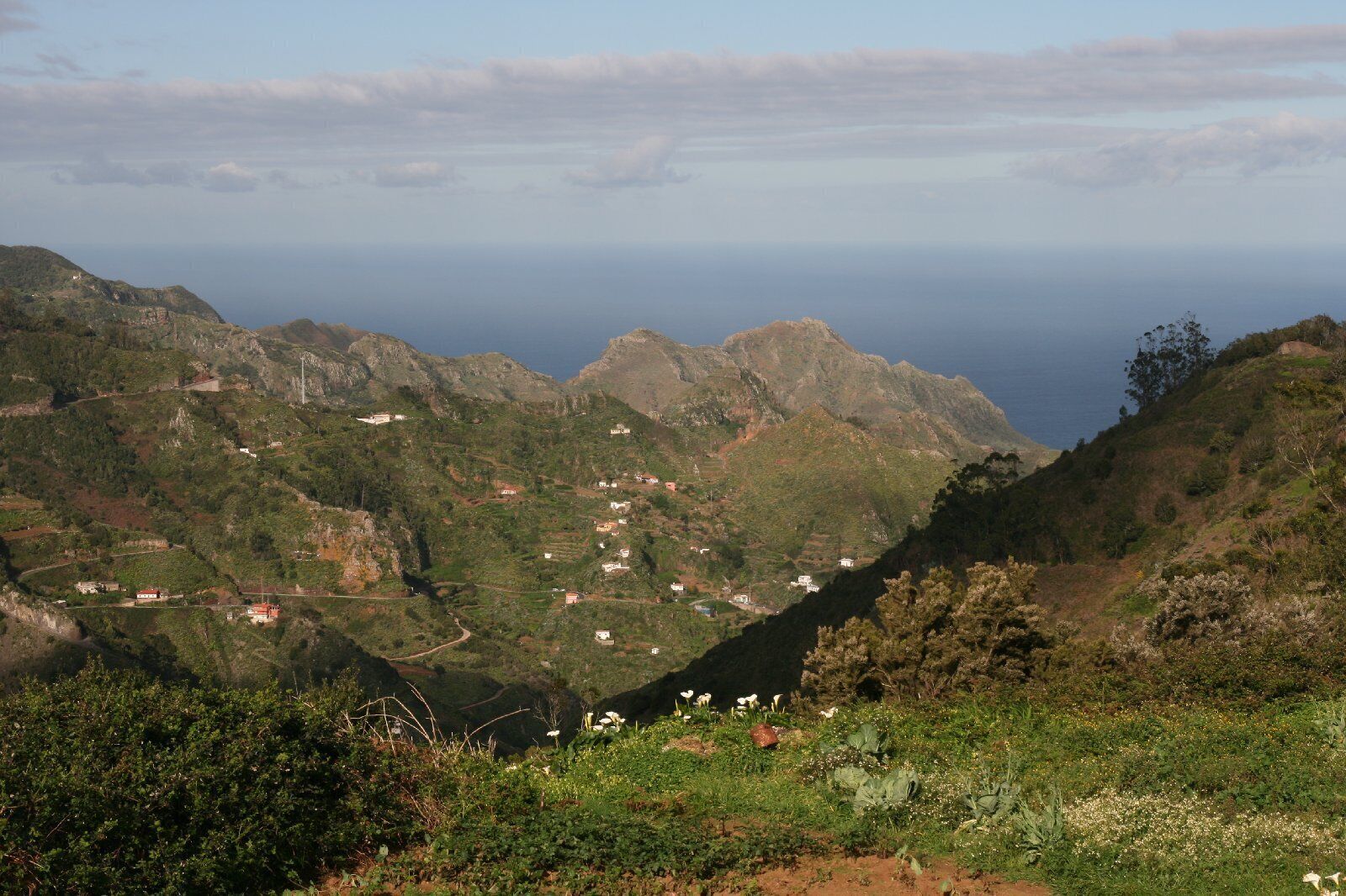 Paisagem montanhosa com casas dispersas e estrada sinuosa.