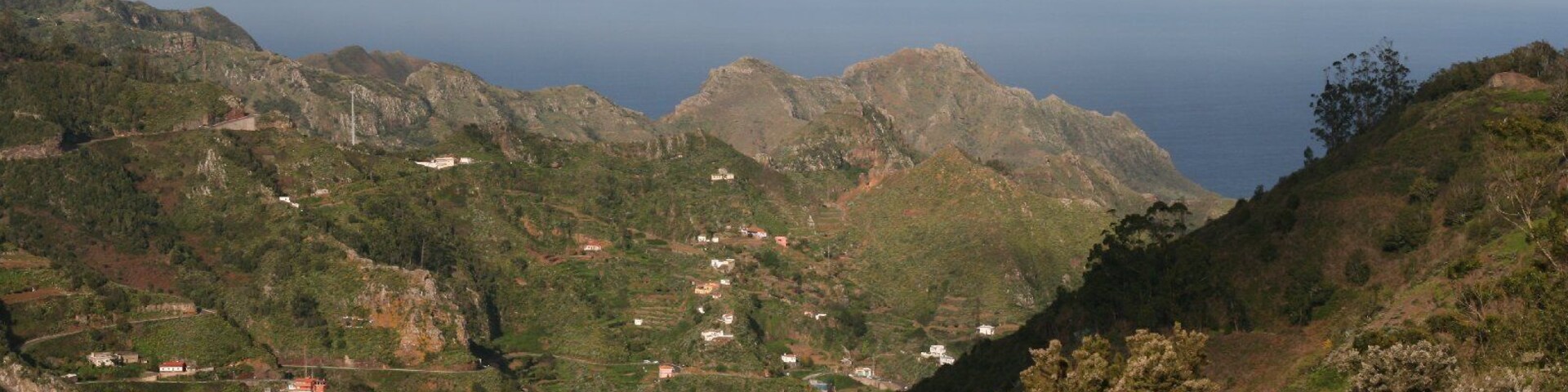 Paisagem montanhosa com casas dispersas e estrada sinuosa.