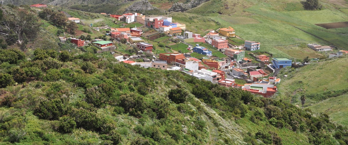 A hillside village with buildings and greenery.