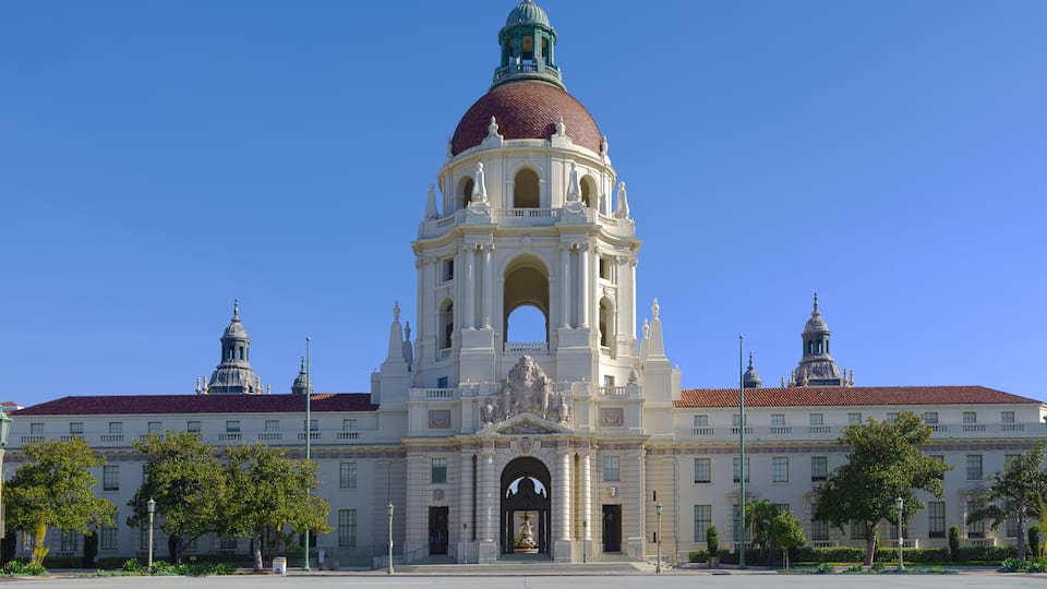 A large white building with a red dome and two smaller domes, surrounded by trees and a clear blue sky.
