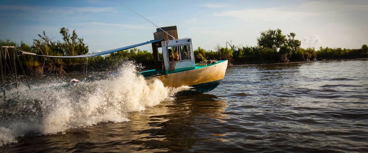 A small boat moving through water with a wake behind it.