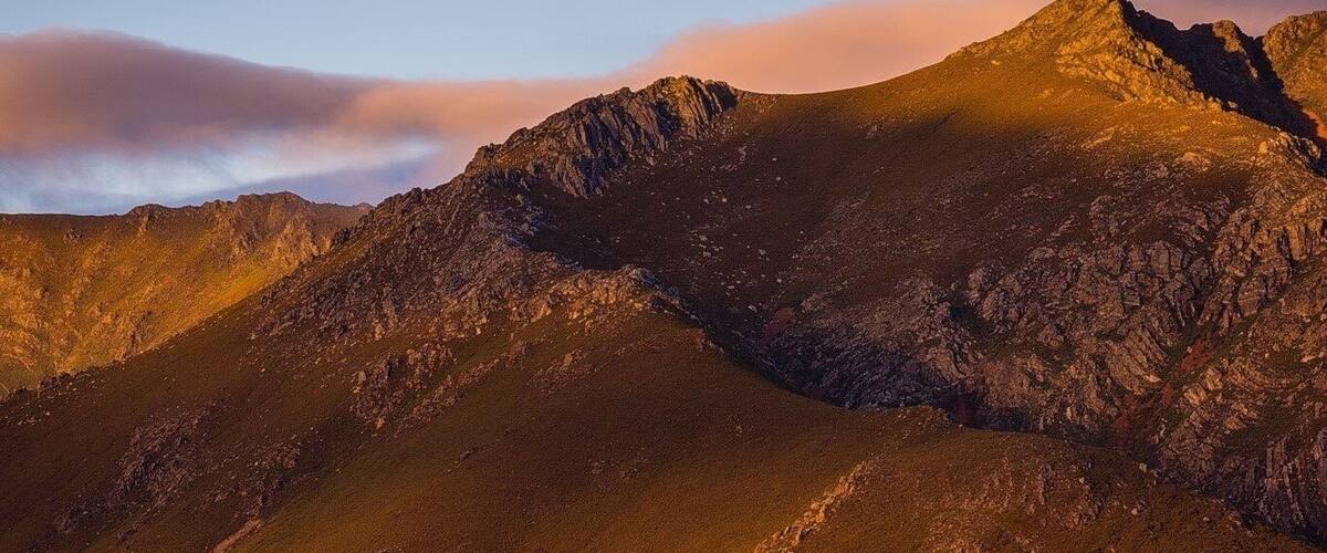 A mountain range with a visible moon in the sky.