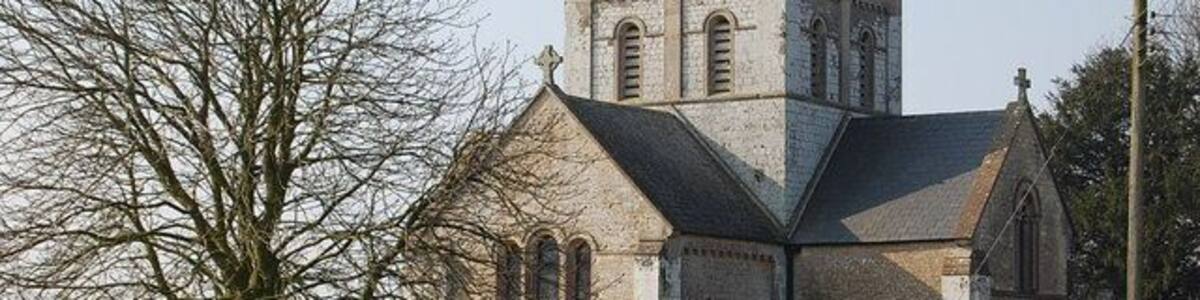 Eine historische Kirche mit einem markanten Turm und einer Steinmauer mit Grabsteinen im Vordergrund.