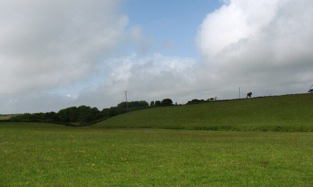 A grassy hill with a cloudy sky.