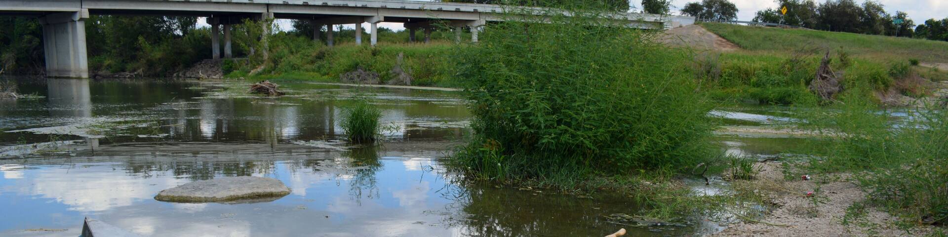 Canoe Beach/Two person canoe sitting on the bank of a river.