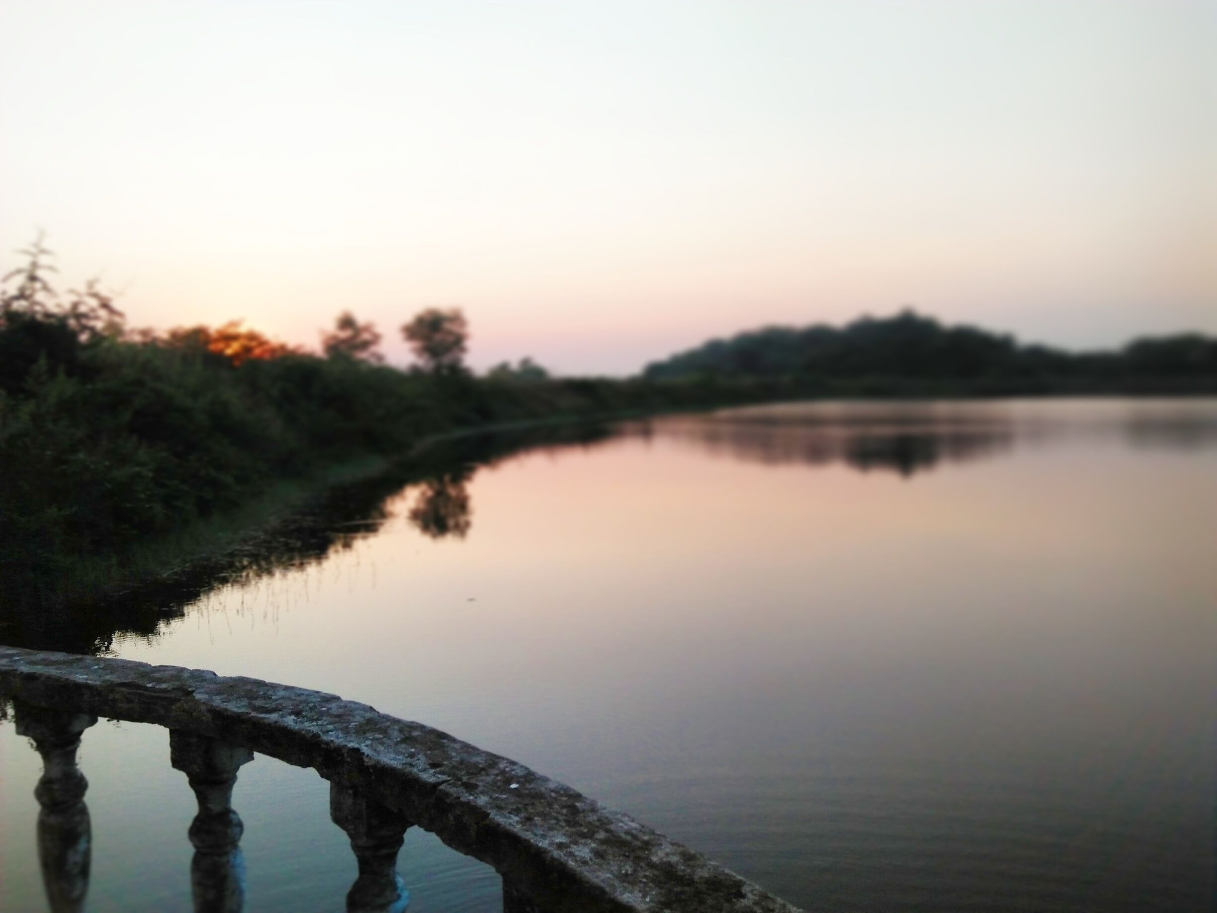 A calm river with a stone bridge in the foreground.