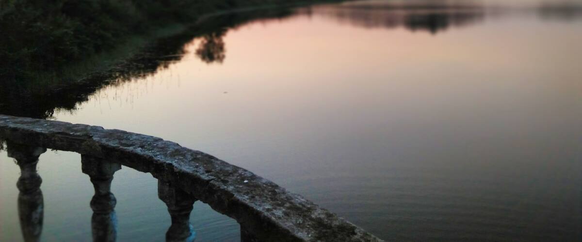 A calm river with a stone bridge in the foreground.