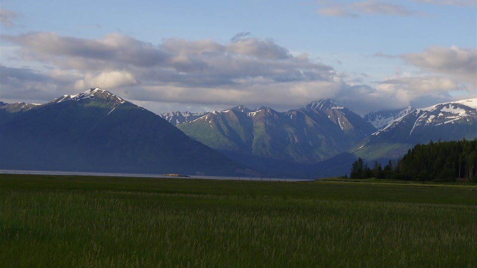 A mountainous landscape with a lake and a grassy field.