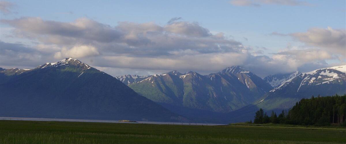 A mountainous landscape with a lake and a grassy field.