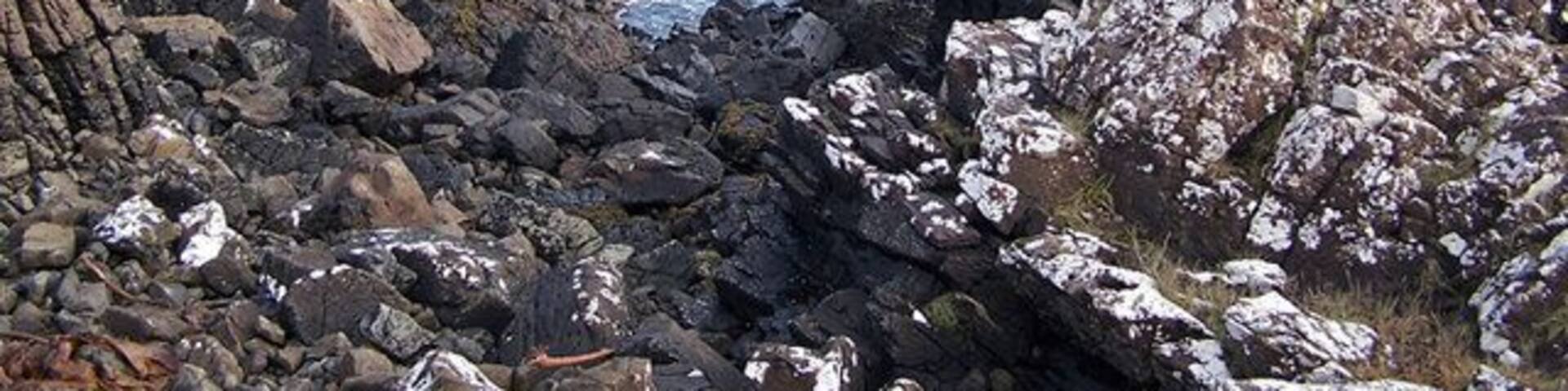A rocky coastline with rugged cliffs and calm sea.