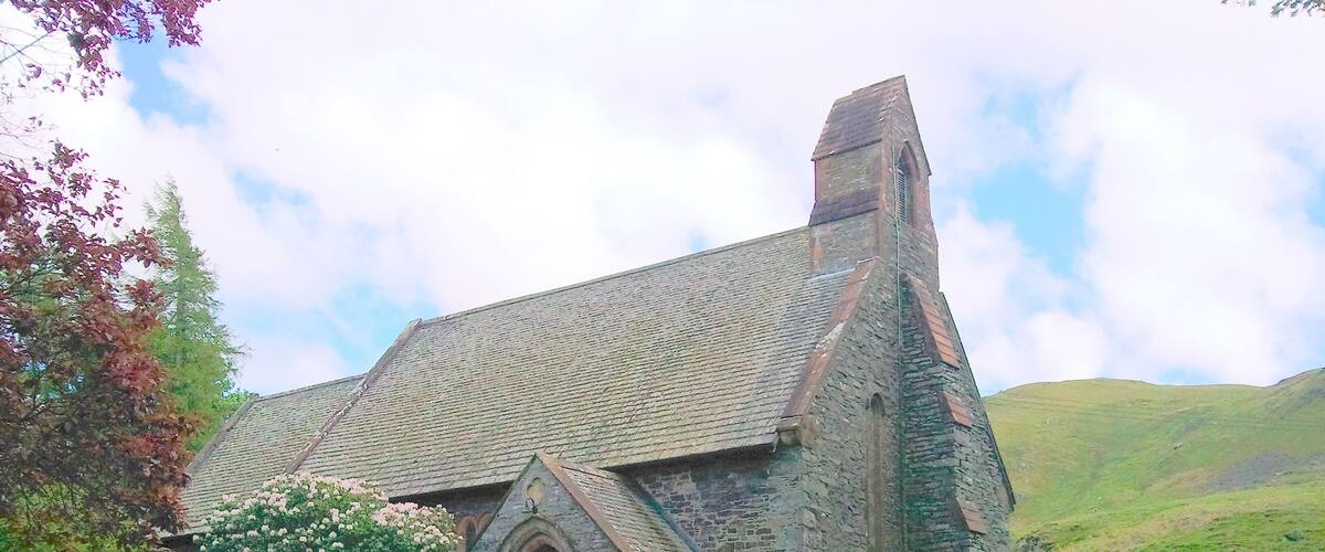 Een stenen kerk met een puntboog en een steil dak.