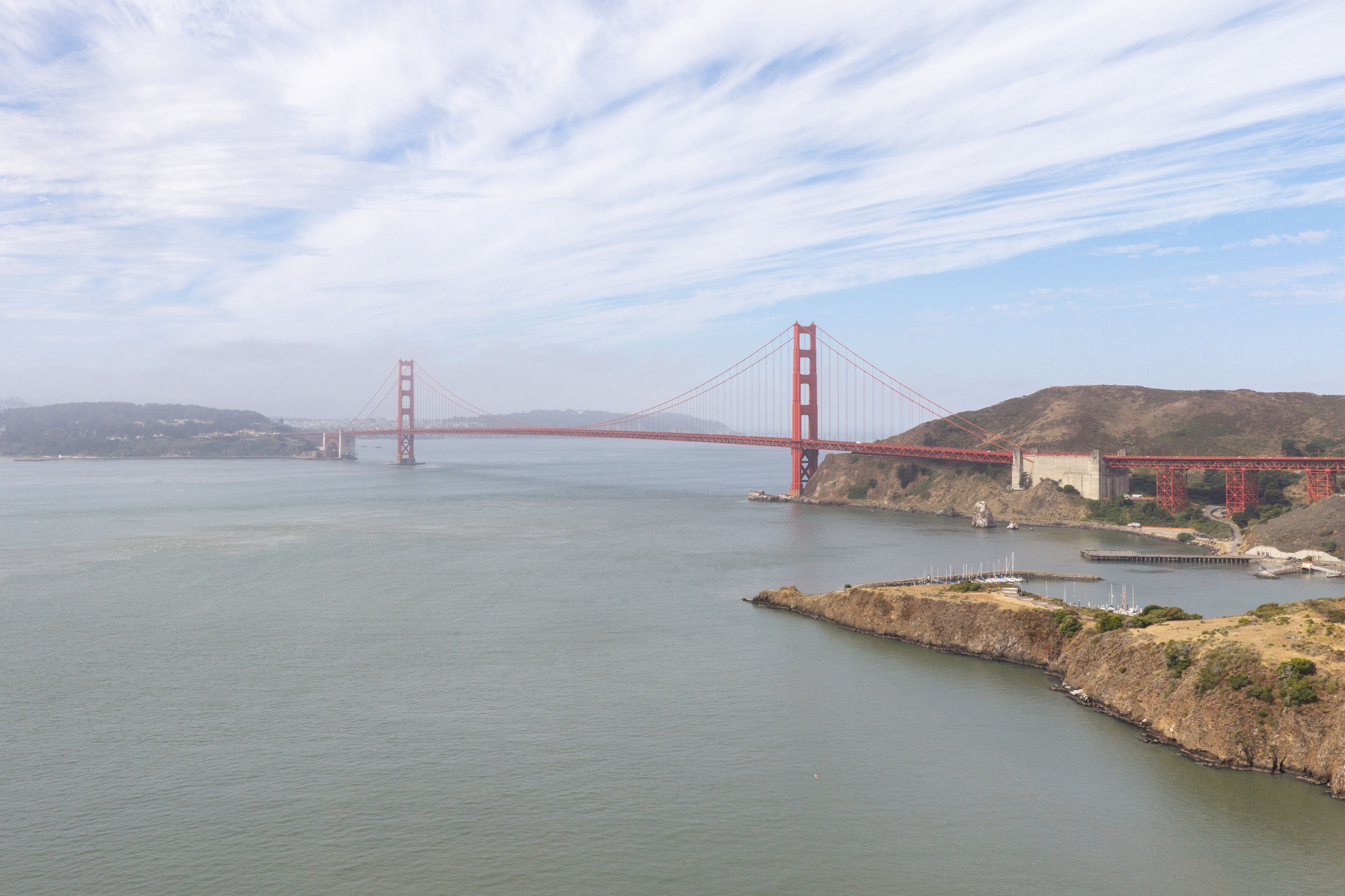 The Golden Gate Bridge spanning a body of water with hills in the background.