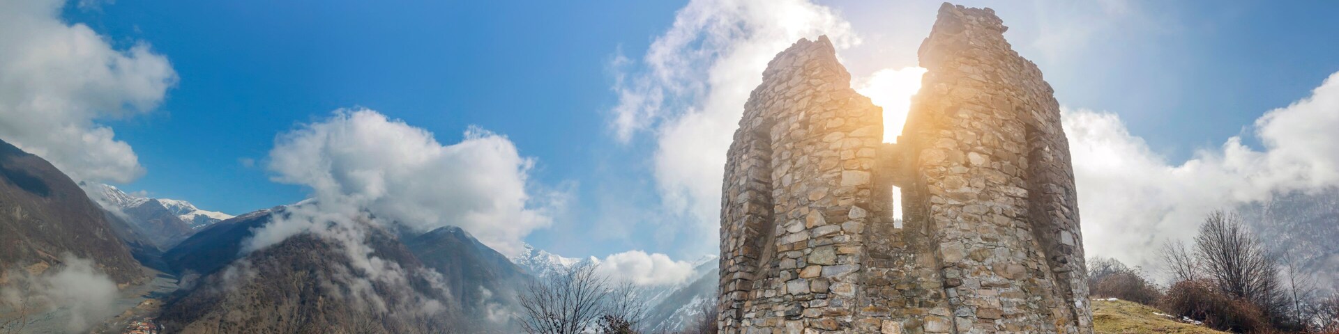 A stone ruin with a clear sky and snow-covered mountains in the background.