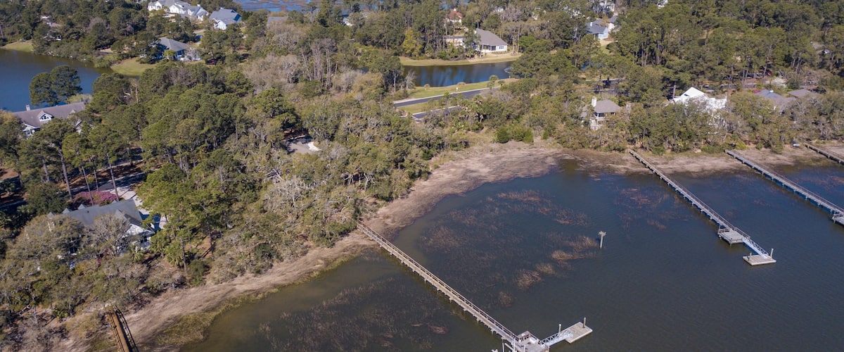 An aerial view of a coastal area with a bridge, docks, and residential buildings.