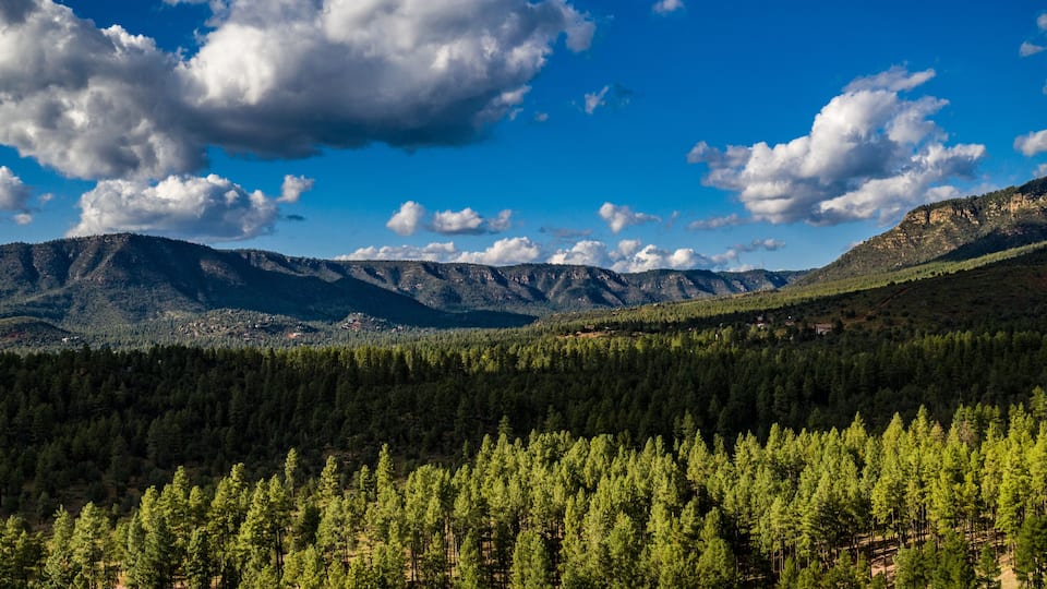 Aerial view of the Tonto National Forest from above the Pine Trailhead in Arizona with blue sky, white clouds and green ponderosa pines
