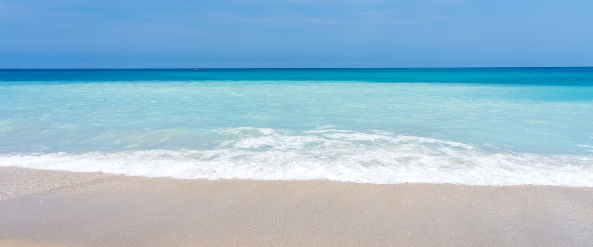 Een strand met helder turquoise water en een zandstrand.