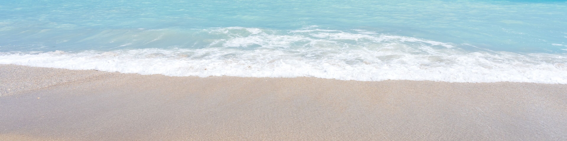 A beach with clear turquoise water and a sandy shore.