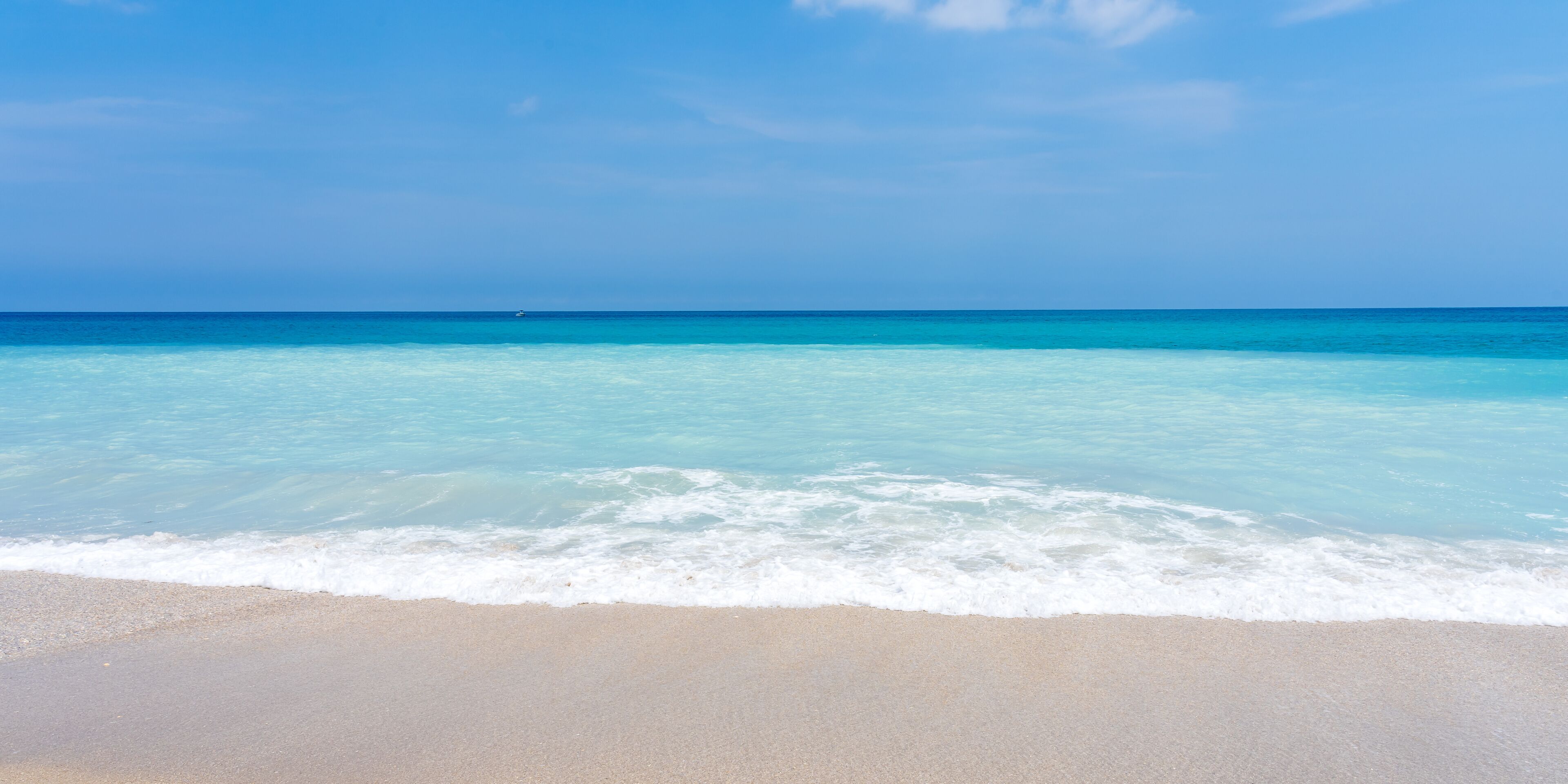 A beach with clear turquoise water and a sandy shore.