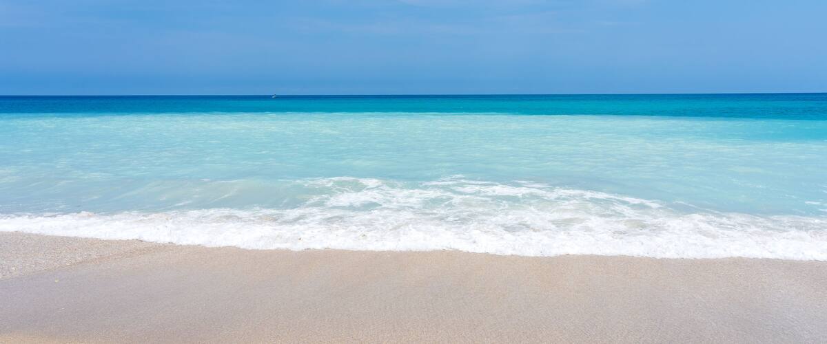 A beach with clear turquoise water and a sandy shore.