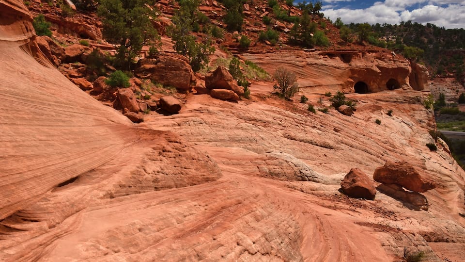 A red rock canyon with layered formations and small caves.