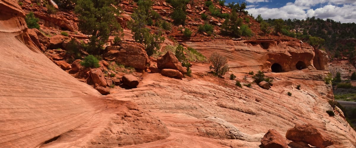 A red rock canyon with layered formations and small caves.