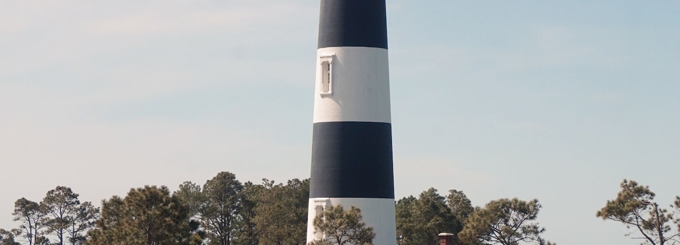 Black and Whtie Striped Body Island Lighthouse, Weathered Wooden Path, Dried Grasses, Sunny Day, Blue Sky
